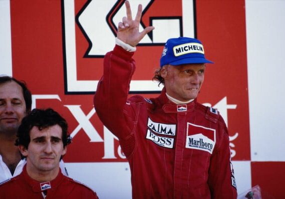 Niki Lauda, driver of the #8 Marlboro McLaren International  MP4-2 TAG 1.5 V6Turbo celebrates his second place and his third World Championship with team mate Alain Prost on 21st October 1984 during the Portuguese Grand Prix at the Autodromo do Estoril in Estoril, Portugal. (Photo by Mike Powell/Getty Images)