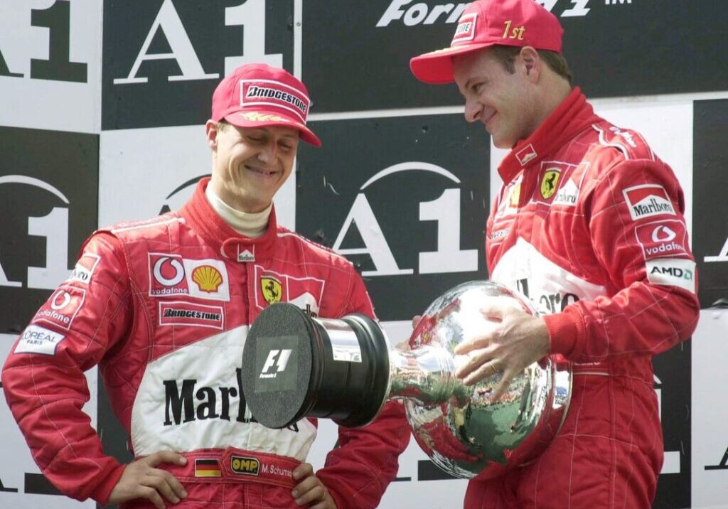 Ferrari driver Rubens Barrichello from Brazil, right, holds the winner's trophy while winner Michael Schumacher from Germany, left, smiles on the podium of the Austrian Grand Prix at the racing track in Spielberg, Austria, on Sunday, May 12, 2002. Michael Schumacher donated the trophy to Barichello who had led from start to finish, because he let Schumacher pass just before the finish line. (AP Photo/Martin Gnedt)